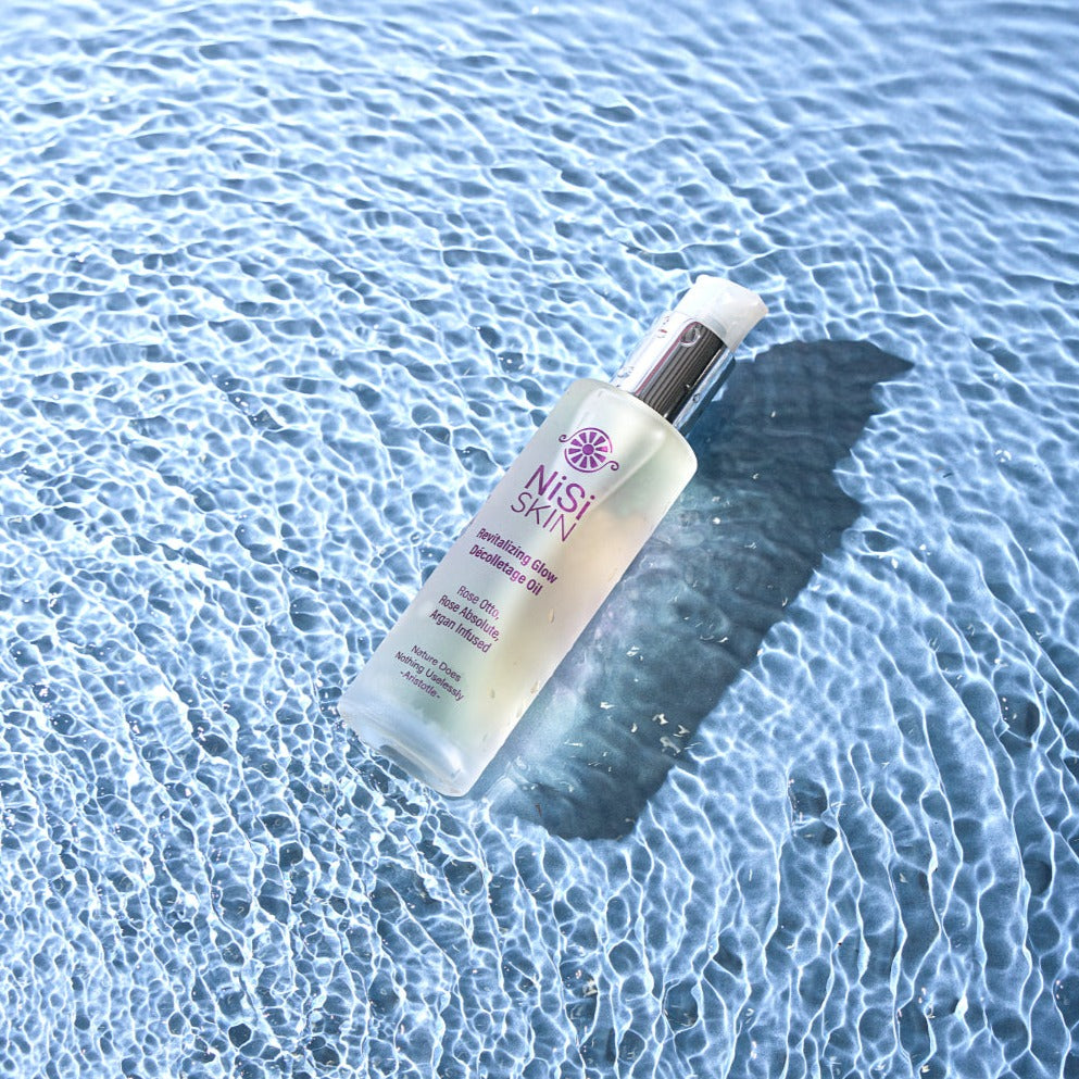 Nisi Skin Decolletage Oil Rose Otto laying in reflective blue water product photography 